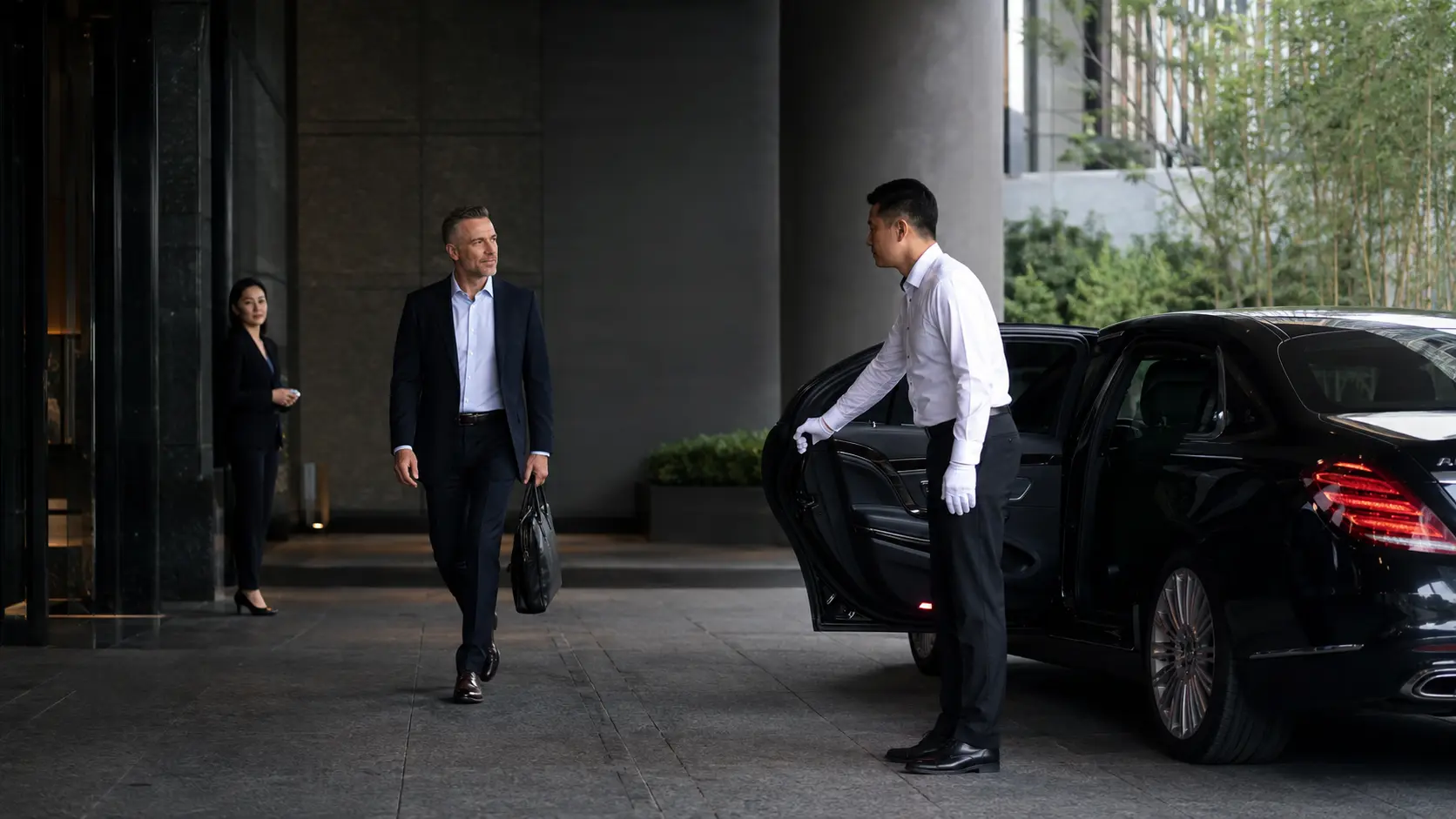 A professional Chinese chauffeur opening an executive sedan for an international business traveller